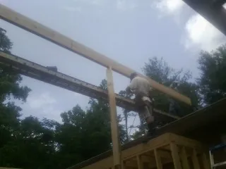 Carpenter setting a ridge beam over a new addition frame — Ice Dam Removal by Roofing Brothers in Brave
