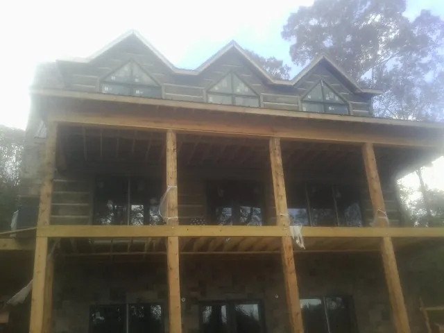 Dormers and porch framing on a large log home under construction — Roof Coating work by our crew in Brave