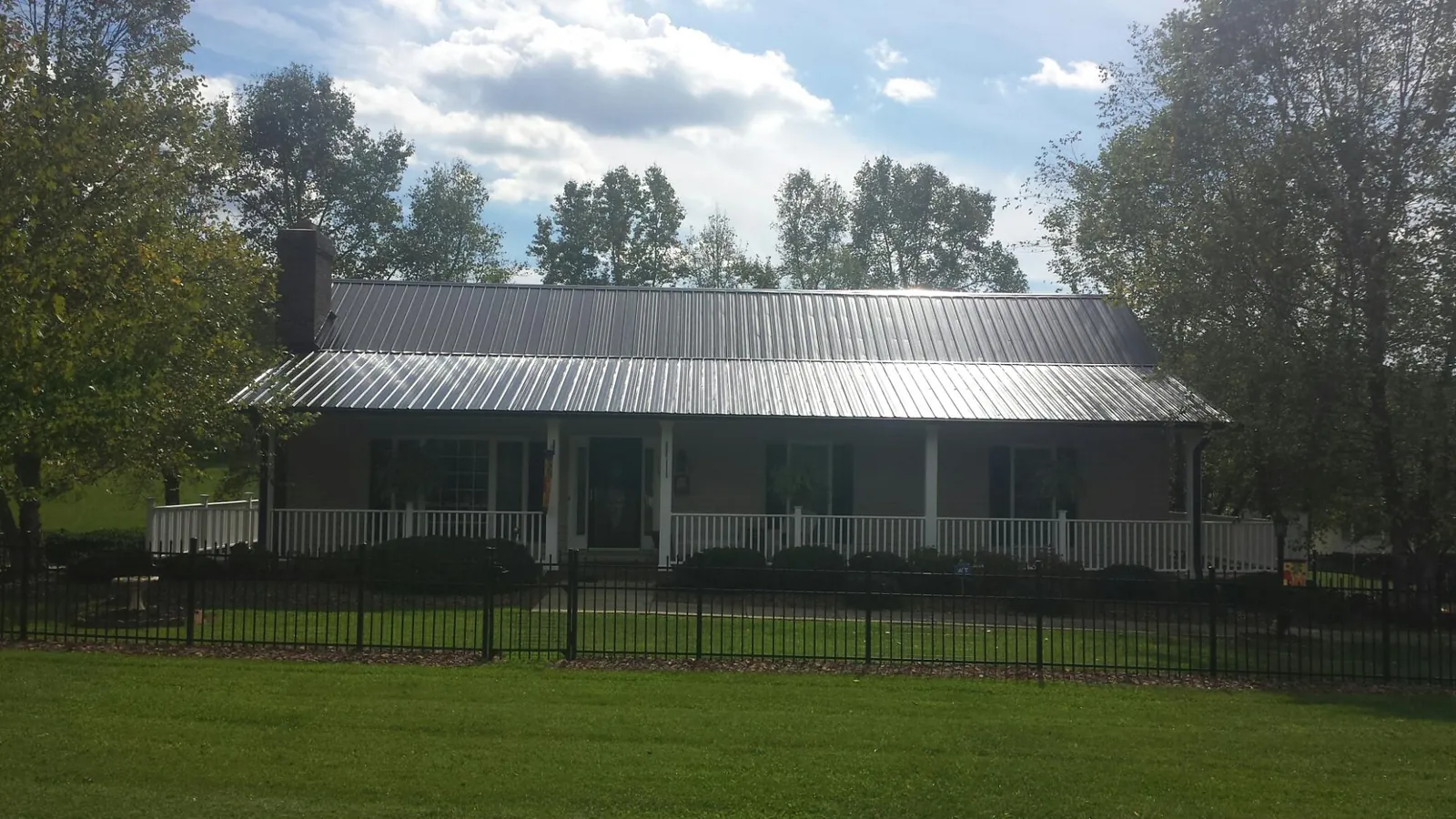 Gray metal roof on a brick ranch with a full width front porch — Gutter Guard Installation work by our crew in Brave