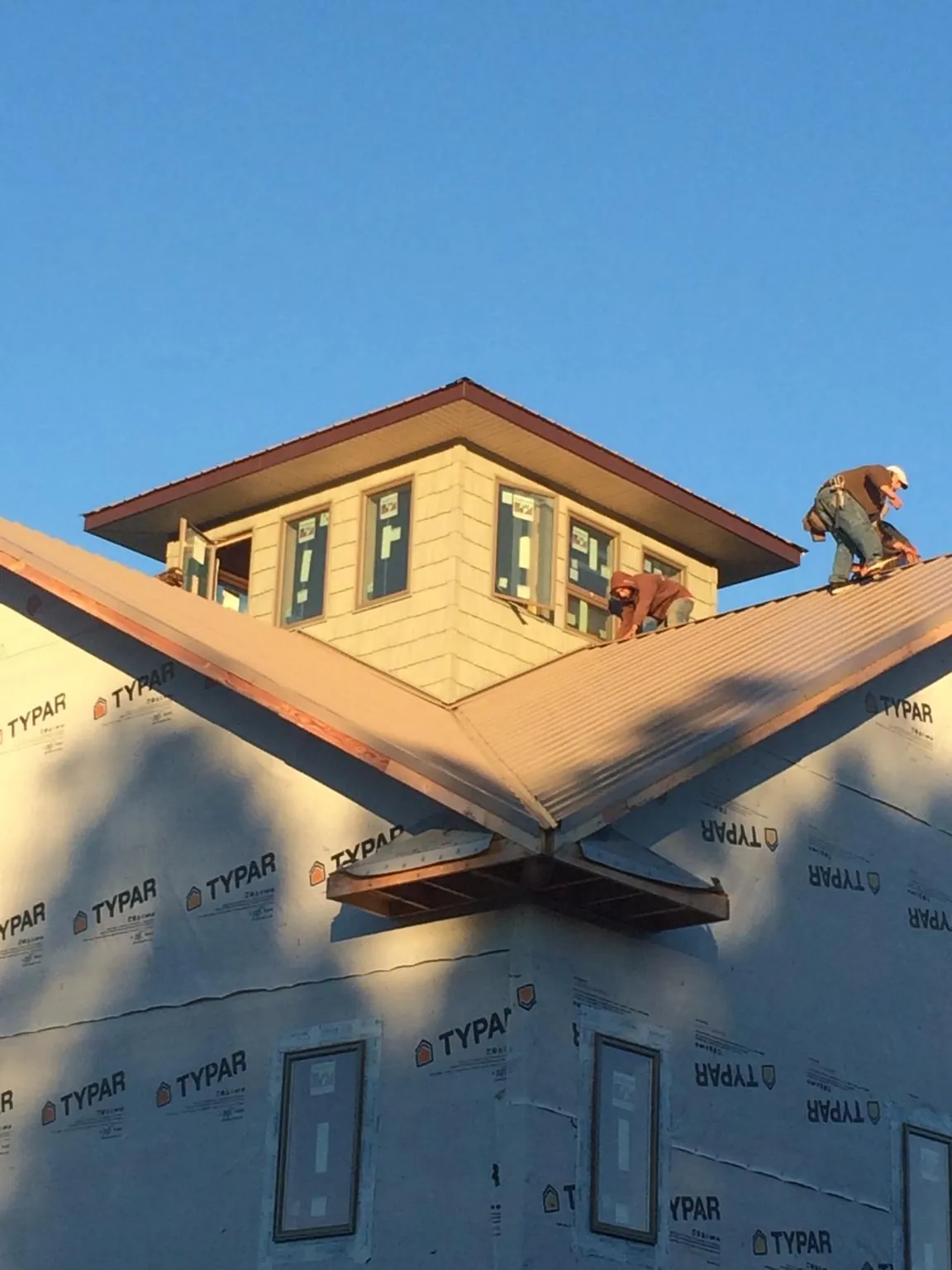 Roofers working around a rooftop cupola on a new metal roof at sunset — Roof Waterproofing in Brave by Roofing Brothers